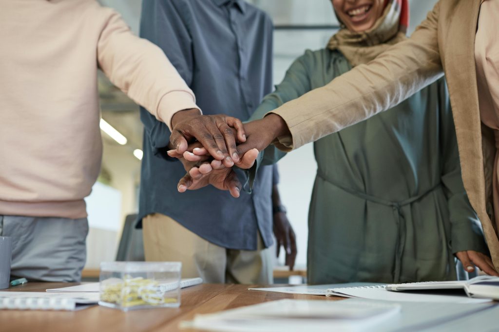 A group of people joining hands in solidarity as a community.