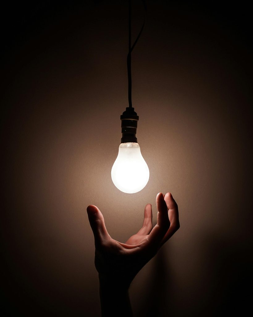 A hand reaching for a bright lightbulb, used to illustrate the idea of someone seeking for a new idea. Your idea is a crucial part of learning easy steps to draw.