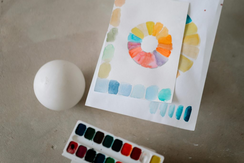 A sphere and various shades of watercolor paints to illustrate the exploration of light and shadow in art.